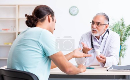 Photo for The young man visiting old male doctor - Royalty Free Image