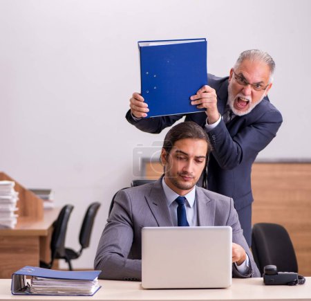 Téléchargez les photos : Vieux patron masculin et jeune assistant masculin dans le bureau - en image libre de droit