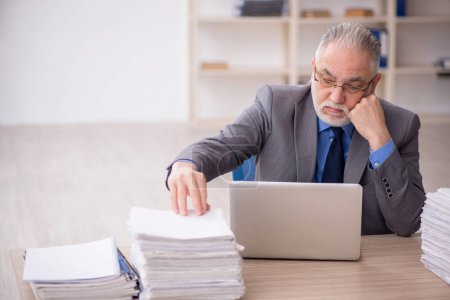 Téléchargez les photos : Old employee and too much work at workplace - en image libre de droit
