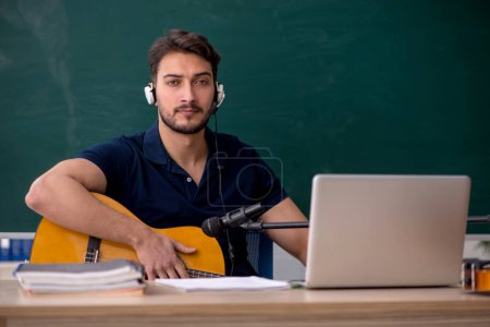 Junge Musiklehrerin sitzt im Klassenzimmer
