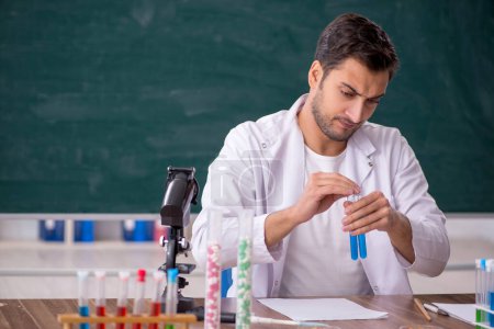 Photo for Young chemist in front of green board - Royalty Free Image