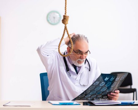 Téléchargez les photos : Vieux médecin se suicidant sur le lieu de travail - en image libre de droit