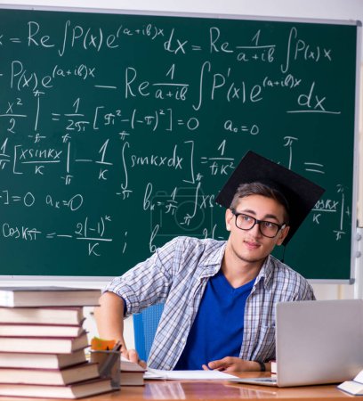 Téléchargez les photos : Le jeune étudiant masculin qui étudie les mathématiques à l'école - en image libre de droit