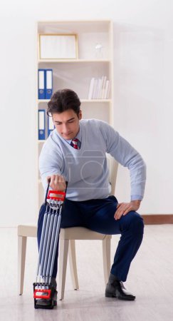 Photo for The man exercising with elastic band in office during lunch break - Royalty Free Image