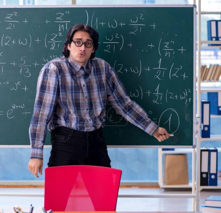 Foto de El joven profesor divertido de matemáticas frente a la pizarra - Imagen libre de derechos
