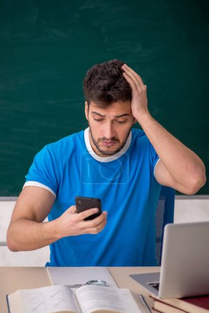 Téléchargez les photos : Jeune étudiant tenant un smartphone en classe - en image libre de droit