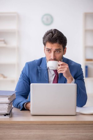 Photo for Young employee drinking coffee during break - Royalty Free Image