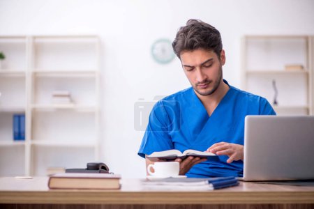 Photo for Young doctor student reading book in the clinic - Royalty Free Image