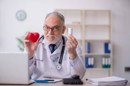 Photo for Old doctor cardiologist working in the clinic - Royalty Free Image