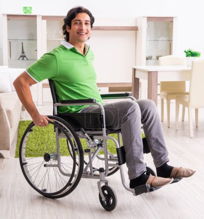 Photo for The young handsome man in wheelchair at home - Royalty Free Image