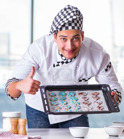 Téléchargez les photos : Le jeune homme cuisine des biscuits dans la cuisine - en image libre de droit