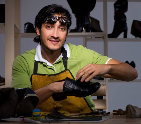 Photo for The young shoemaker in workshop at night - Royalty Free Image