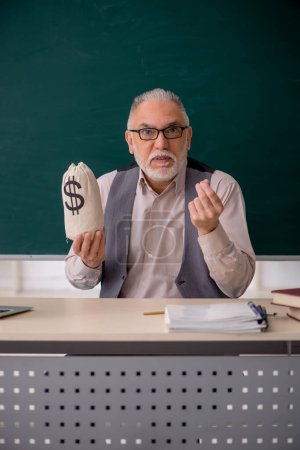 Photo for Old male teacher holding moneybag - Royalty Free Image