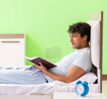 Téléchargez les photos : Le jeune étudiant beau livre de lecture dans le lit - en image libre de droit