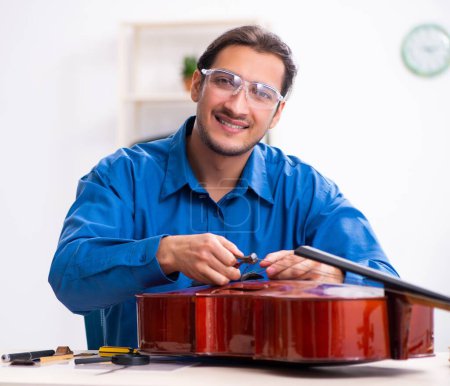 Foto de Hombre joven reparador reparando el violonchelo - Imagen libre de derechos