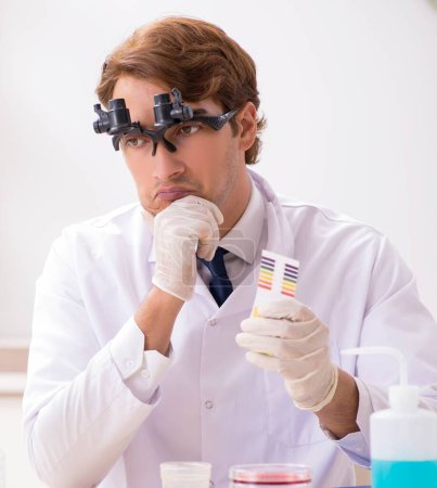 Téléchargez les photos : Le chimiste au labo vérifie avec des bandelettes ph - en image libre de droit