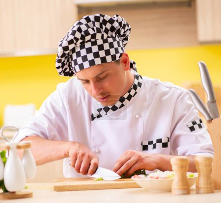 Téléchargez les photos : Le jeune cuisinier professionnel prépare la salade à la cuisine - en image libre de droit