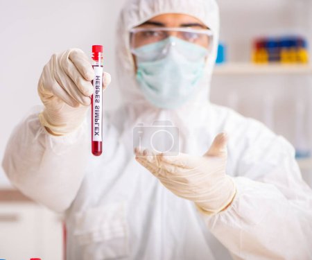 Foto de El joven asistente de laboratorio guapo analizando muestras de sangre en el hospital - Imagen libre de derechos