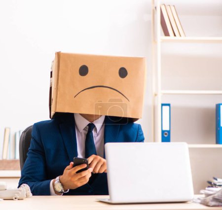Téléchargez les photos : The unhappy man employee with box instead of his head - en image libre de droit