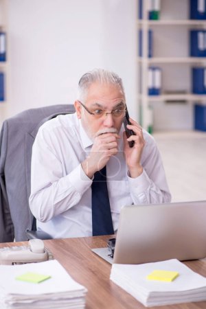 Téléchargez les photos : Old businessman employee unhappy with excessive work at workplace - en image libre de droit