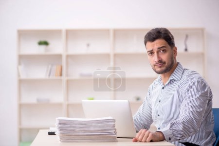 Téléchargez les photos : Jeune employé masculin assis sur le lieu de travail - en image libre de droit