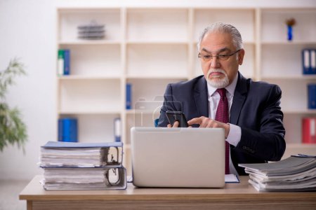 Téléchargez les photos : Vieil homme d'affaires employé travaillant dans le bureau - en image libre de droit