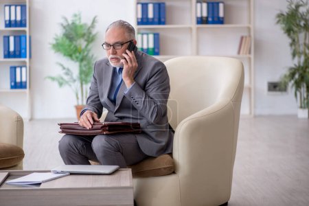 Foto de Viejo empleado hablando por teléfono en la oficina - Imagen libre de derechos