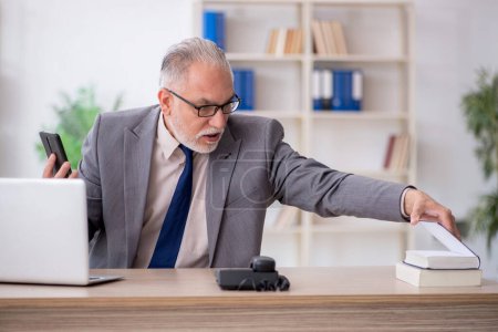 Téléchargez les photos : Ancien employé parlant par téléphone sur le lieu de travail - en image libre de droit