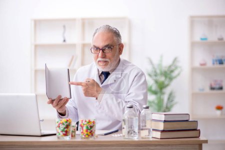 Téléchargez les photos : Vieux médecin tenant le livre à la clinique - en image libre de droit