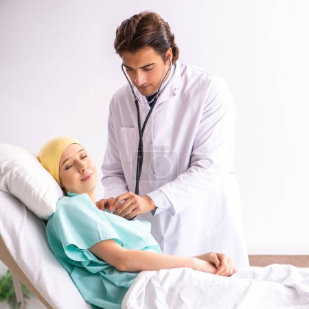 Foto de El joven y guapo doctor visitando a una paciente de oncología femenina - Imagen libre de derechos