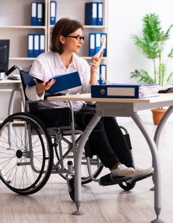 Foto de La empleada en silla de ruedas en la oficina - Imagen libre de derechos