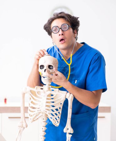 Téléchargez les photos : Le médecin drôle avec squelette à l'hôpital - en image libre de droit