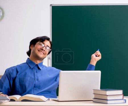 Photo for The young male teacher in front of chalkboard - Royalty Free Image