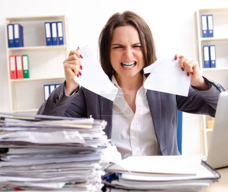 Téléchargez les photos : The young female employee unhappy with excessive work - en image libre de droit