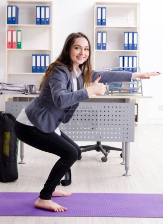 The female employee doing sport exercises in the office