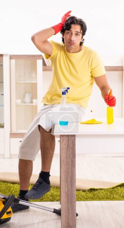 Téléchargez les photos : Le jeune homme beau faisant des travaux ménagers - en image libre de droit