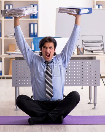 Photo for The young handsome male employee doing exercises in the office - Royalty Free Image