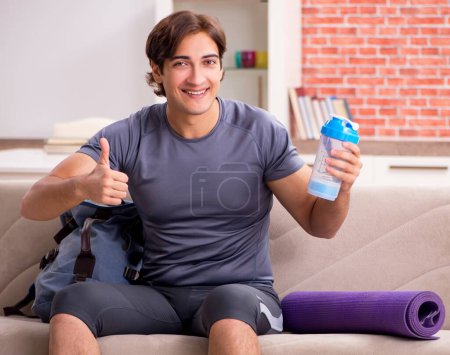 Photo for The young handsome man doing sport exercises at home - Royalty Free Image