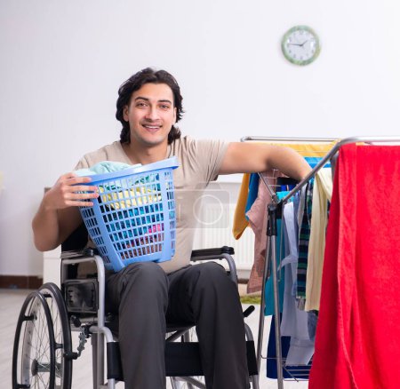 Photo for The young man in wheel-chair doing ironing at home - Royalty Free Image