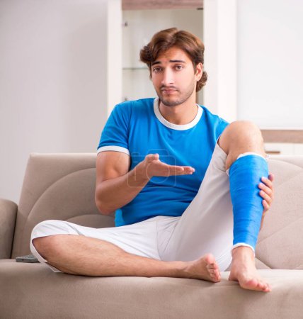 Photo for The leg injured young man on the sofa - Royalty Free Image