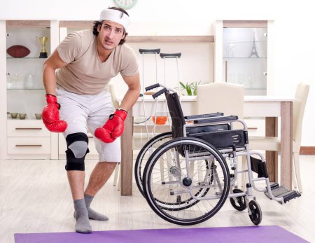 Téléchargez les photos : Le jeune homme blessé faisant des exercices à la maison - en image libre de droit