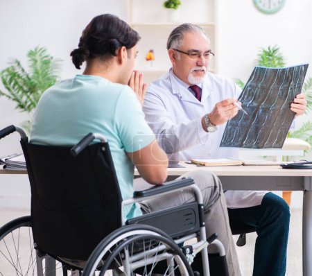 Téléchargez les photos : Le patient masculin en fauteuil roulant visitant un vieux médecin - en image libre de droit