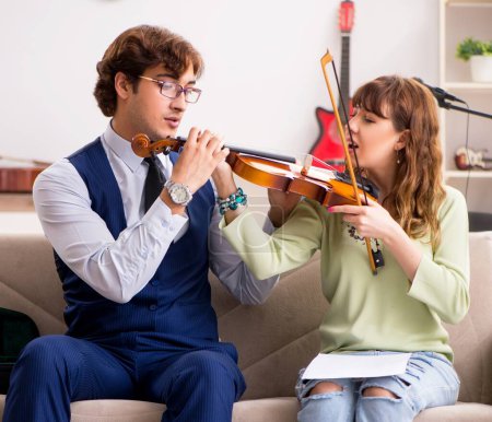 Téléchargez les photos : La jeune femme pendant le cours de musique avec le professeur masculin - en image libre de droit