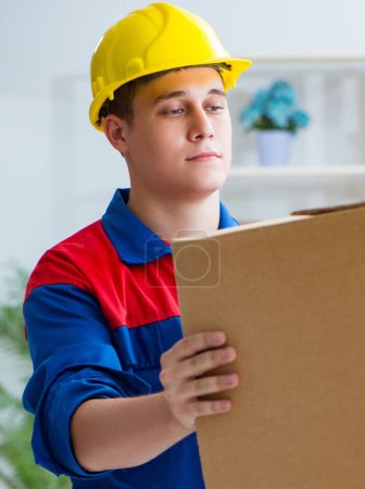 Téléchargez les photos : Le jeune homme travaillant dans les services de déménagement avec des boîtes - en image libre de droit