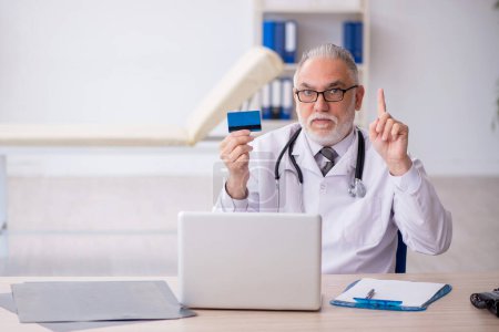 Photo for Old doctor holding credit card - Royalty Free Image