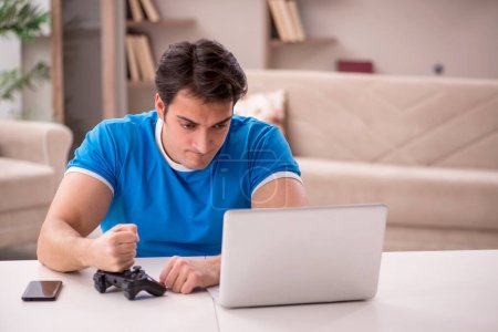 Photo for Young male student playing video games at home - Royalty Free Image