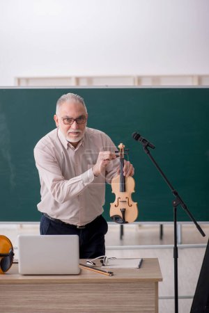 Téléchargez les photos : Vieil enseignant jouant du violon en classe - en image libre de droit
