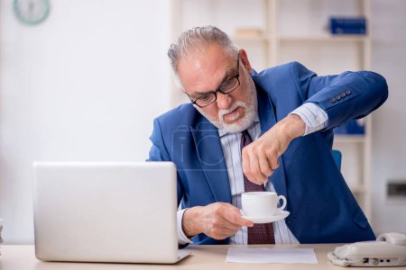 Téléchargez les photos : Vieil employé boire du café pendant la pause - en image libre de droit