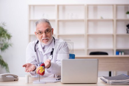 Téléchargez les photos : Vieux médecin cardiologue travaillant à la clinique - en image libre de droit
