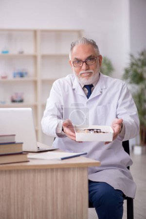 Téléchargez les photos : Old doctor suggesting pills at the hospital - en image libre de droit